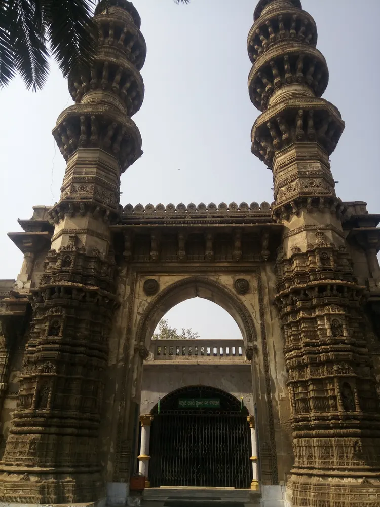 Twin carved sandstone minarets and central arch at Jhulta Minara in Ahmedabad
