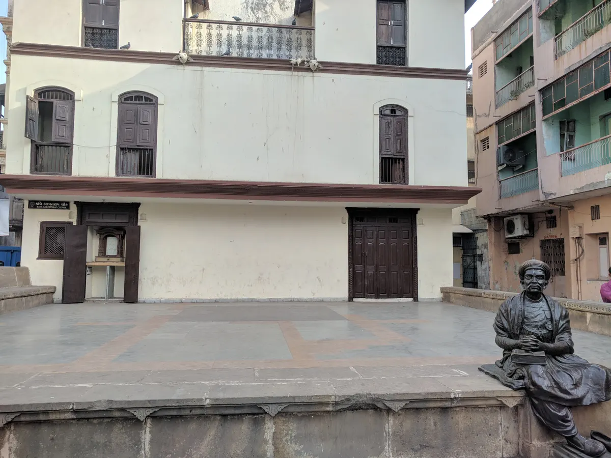 Kavi Dalpatram memorial statue seated beside the open square and replica house façade in Ahmedabad