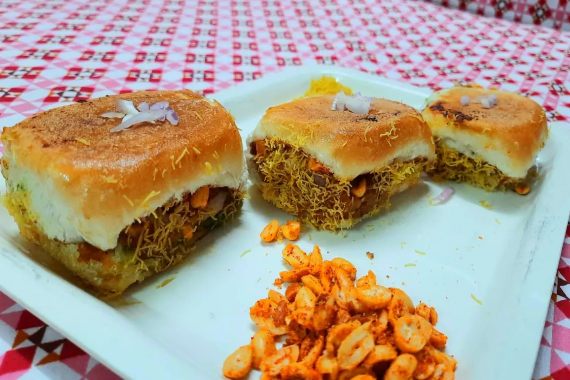 Three pieces of Kutchi dabeli in bread rolls with sev and roasted peanuts
