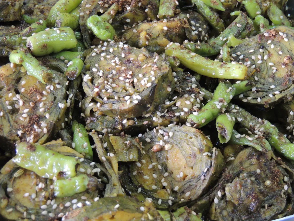 Sliced Gujarati patra rolls tempered with sesame seeds and served with green chillies